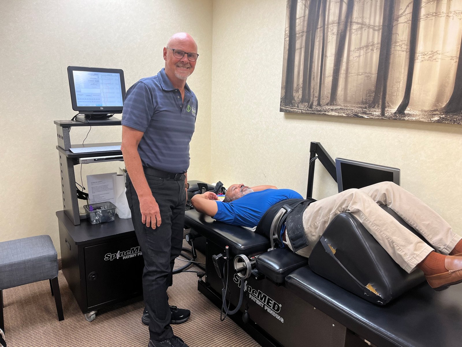 Dr. Charles Arndt standing beside the SpineMED decompression table while a patient lies on it